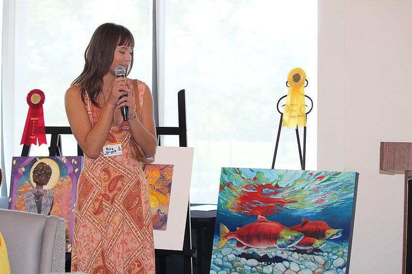 Ada Voight speaking beside her salmon painting.